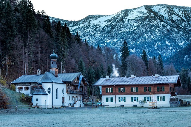 Алпийски пейзаж с планинска църква, заснежени върхове и зимно спокойствие.