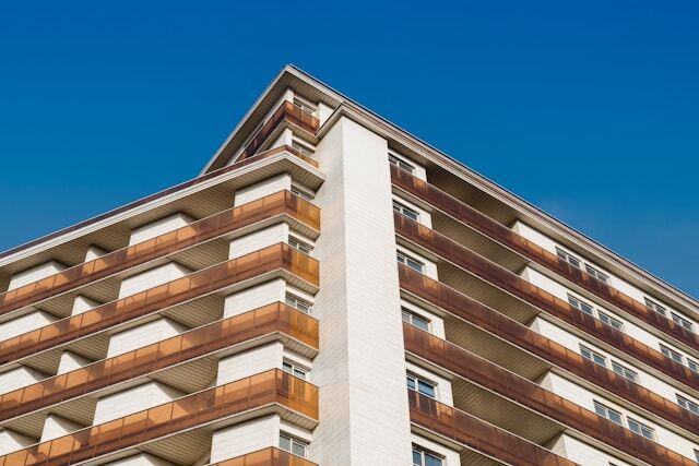 Модерна жилищна сграда с бели фасади, метални балкони и съвременен градски дизайн.